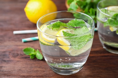 Photo of Tasty refreshing lemonade on wooden table, closeup. Summer drink