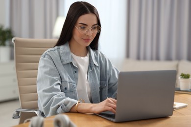 Young woman watching webinar at table in room