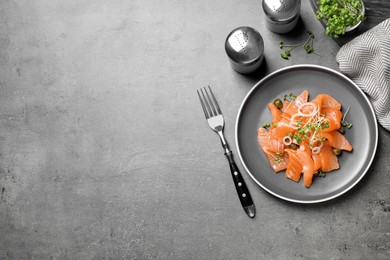 Photo of Salmon carpaccio with capers, onion and microgreens on grey table, flat lay. Space for text