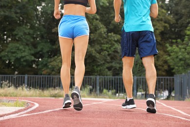 Photo of Healthy lifestyle. Sporty couple running at stadium, closeup
