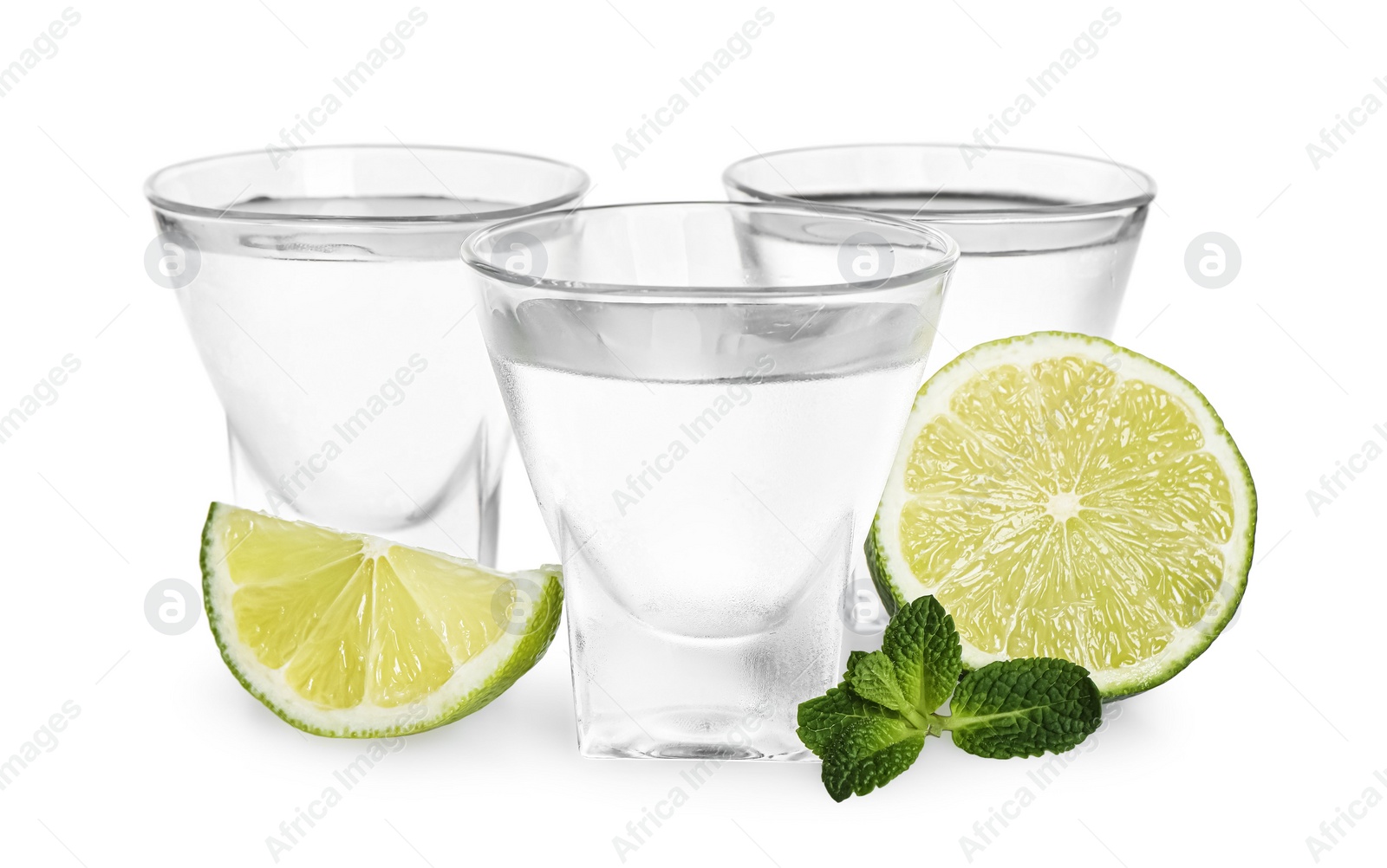 Photo of Shot glasses of vodka with lime and mint on white background