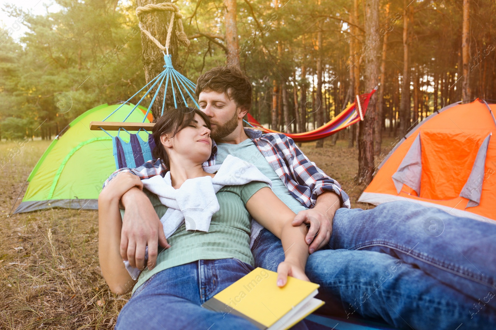 Photo of Lovely couple with book resting in comfortable hammock outdoors