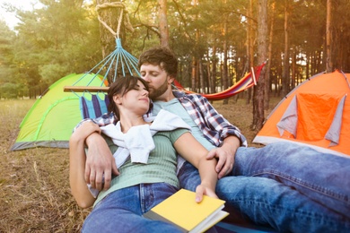 Photo of Lovely couple with book resting in comfortable hammock outdoors