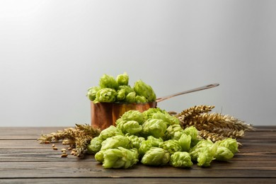 Fresh hop flowers and wheat ears on wooden table against white background