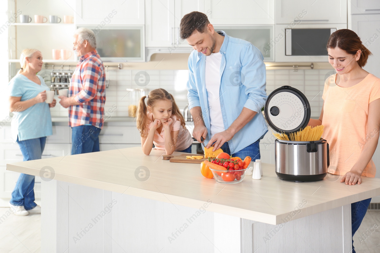 Photo of Happy family preparing food with modern multi cooker in kitchen