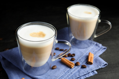 Photo of Delicious latte macchiato, cinnamon and coffee beans on grey table