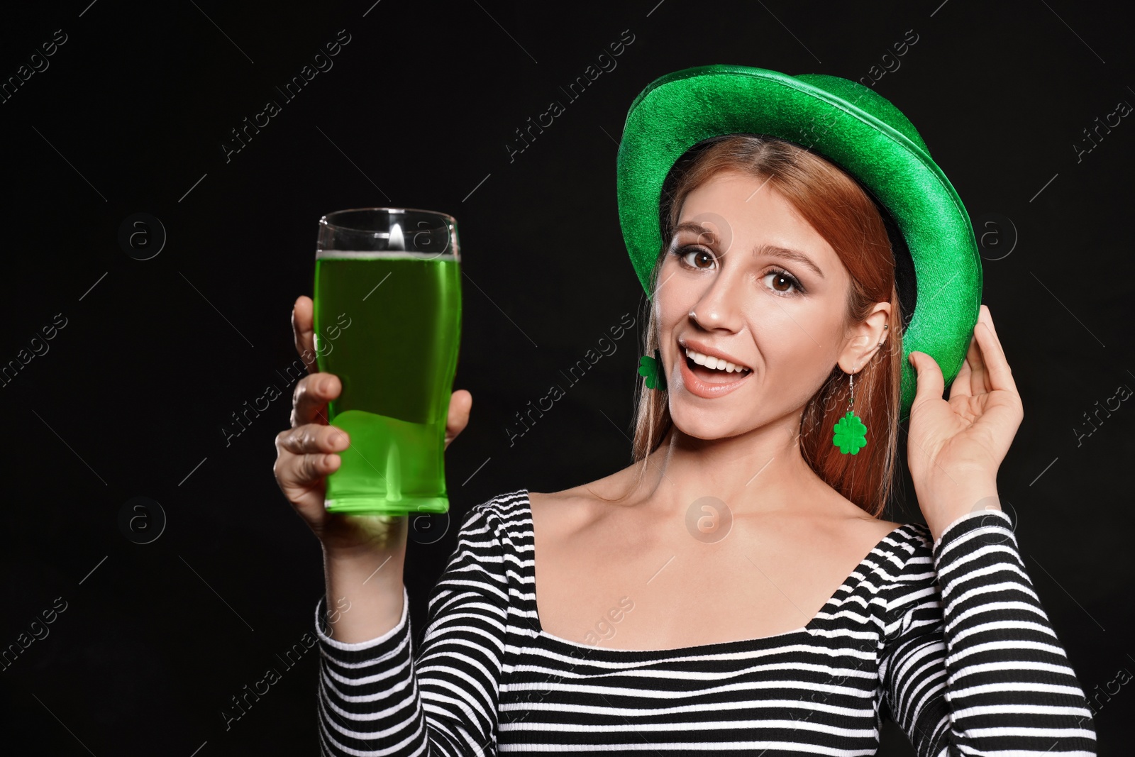 Photo of Young woman with green beer on black background. St. Patrick's Day celebration