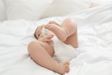 Cute little baby in diaper on bed