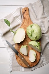 Photo of Whole and cut kohlrabi plants on white wooden table, flat lay
