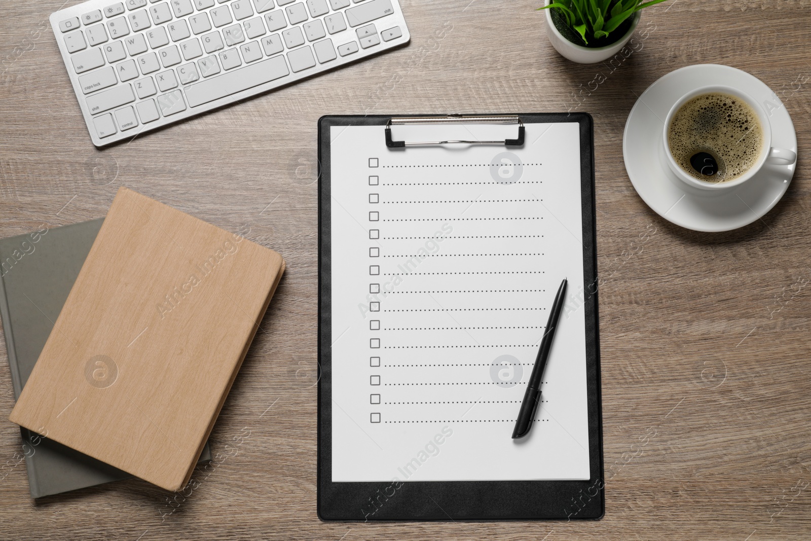 Photo of Clipboard with checkboxes, cup of coffee, plant and computer keyboard on wooden table, flat lay. Checklist