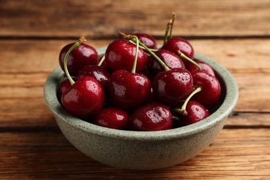 Photo of Bowl with ripe sweet cherries on wooden table, closeup