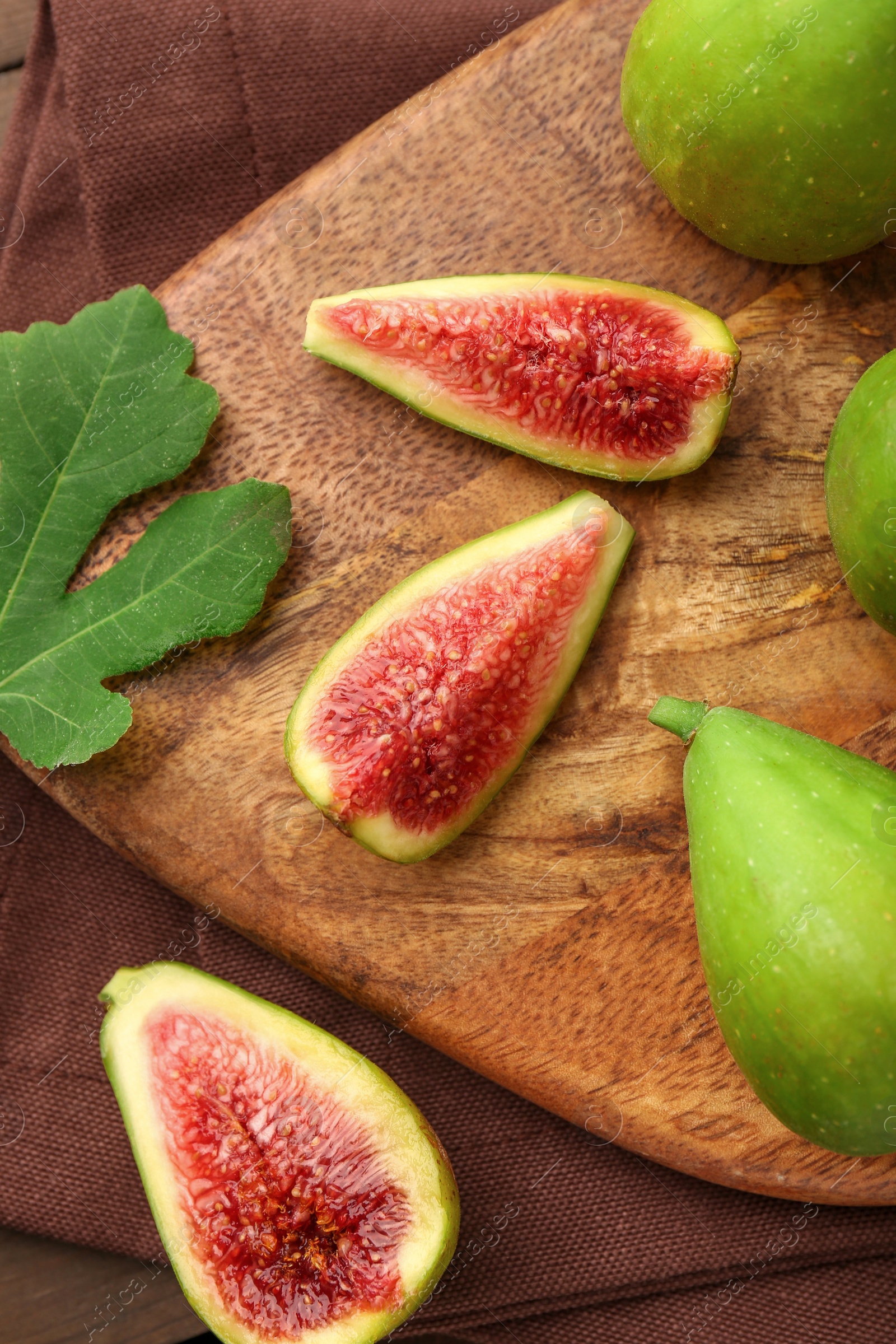 Photo of Cut and whole green figs on wooden table, flat lay