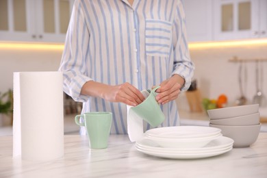 Photo of Woman wiping cup with paper towel in kitchen, closeup