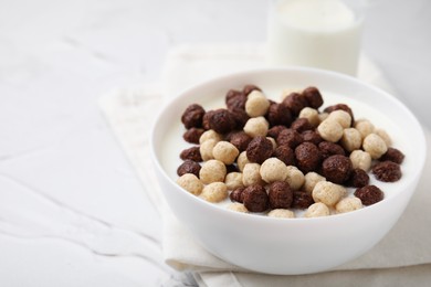 Photo of Breakfast cereal. Tasty corn balls with milk in bowl on white textured table, closeup. Space for text