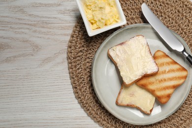 Photo of Tasty toasts with butter on white wooden table, flat lay. Space for text