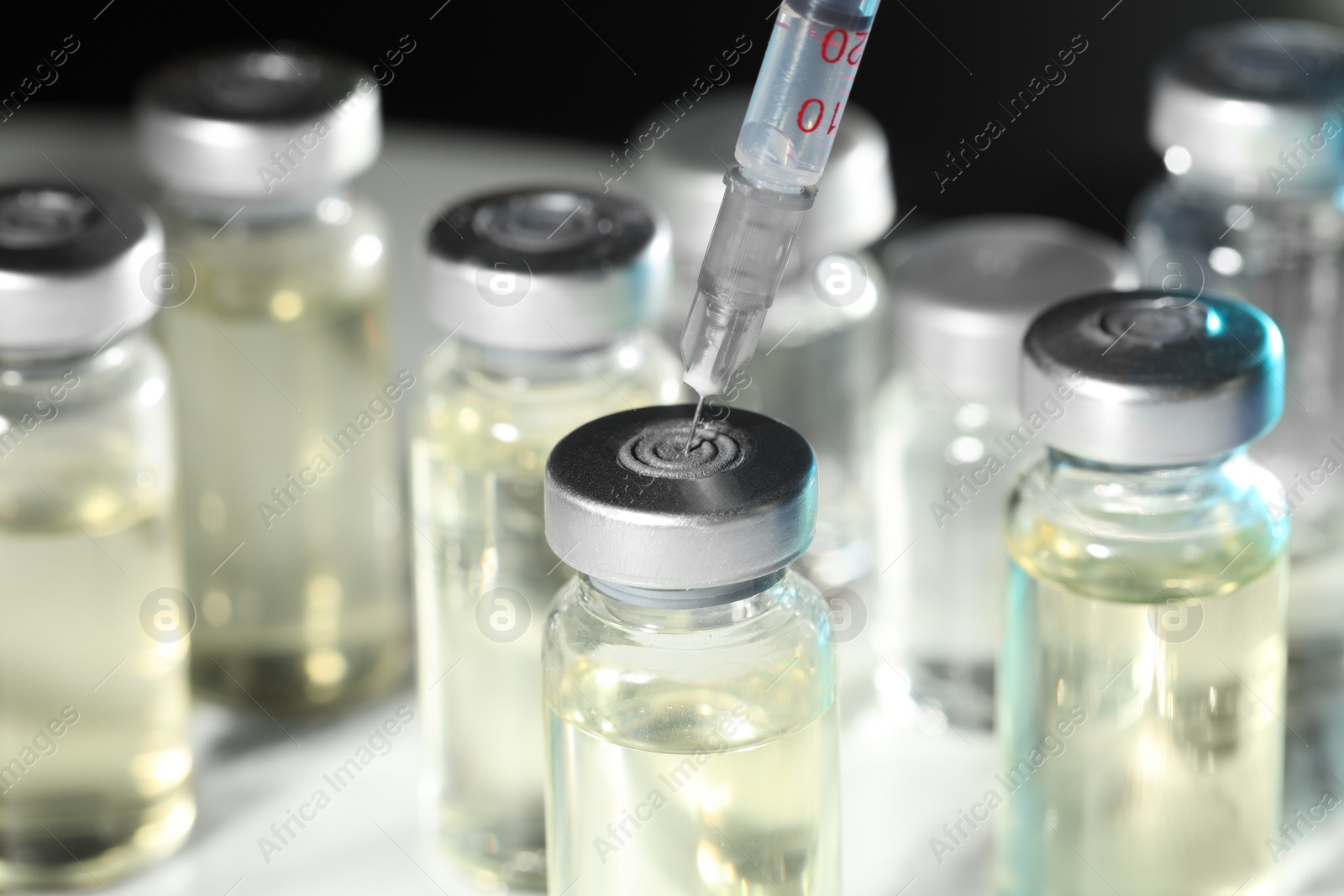 Photo of Filling syringe with medicine from vial on table, closeup