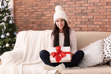 Photo of Beautiful young woman in hat with gift box at home. Christmas celebration