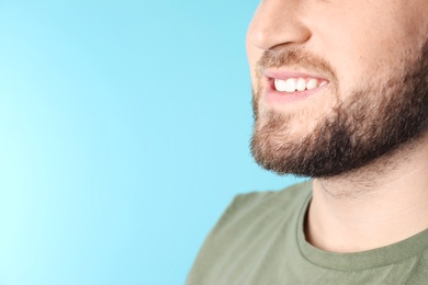 Photo of Young man with healthy teeth on color background, closeup. Space for text