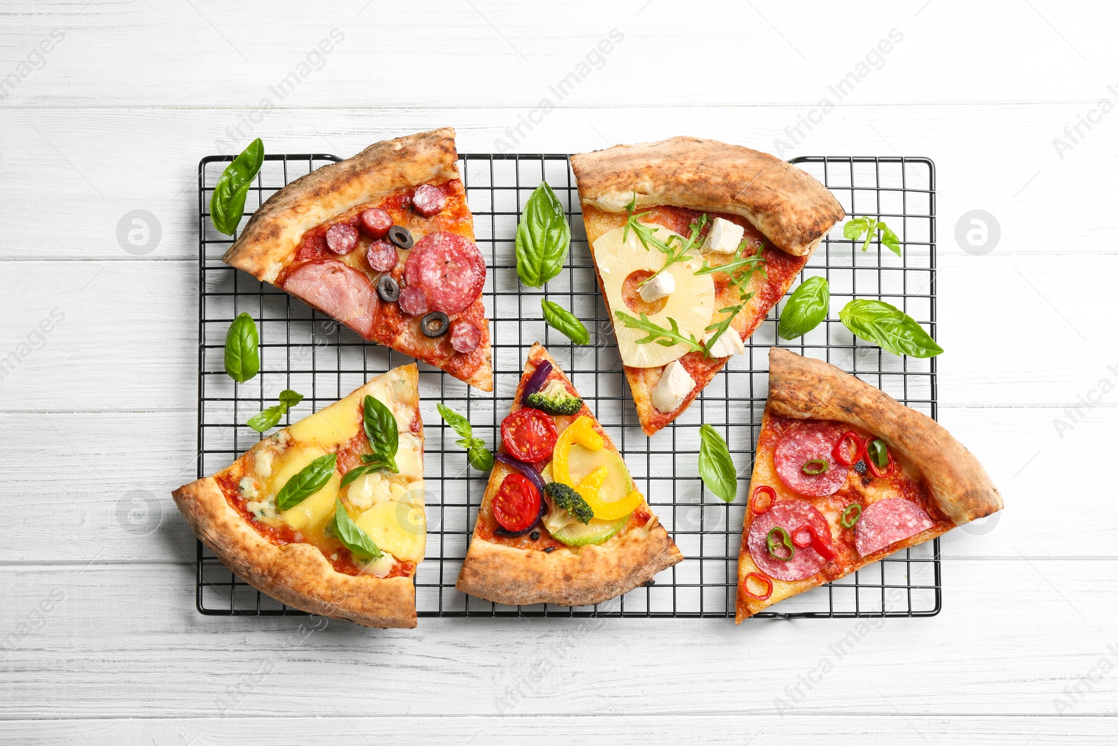 Photo of Slices of different delicious pizzas on white wooden table, flat lay