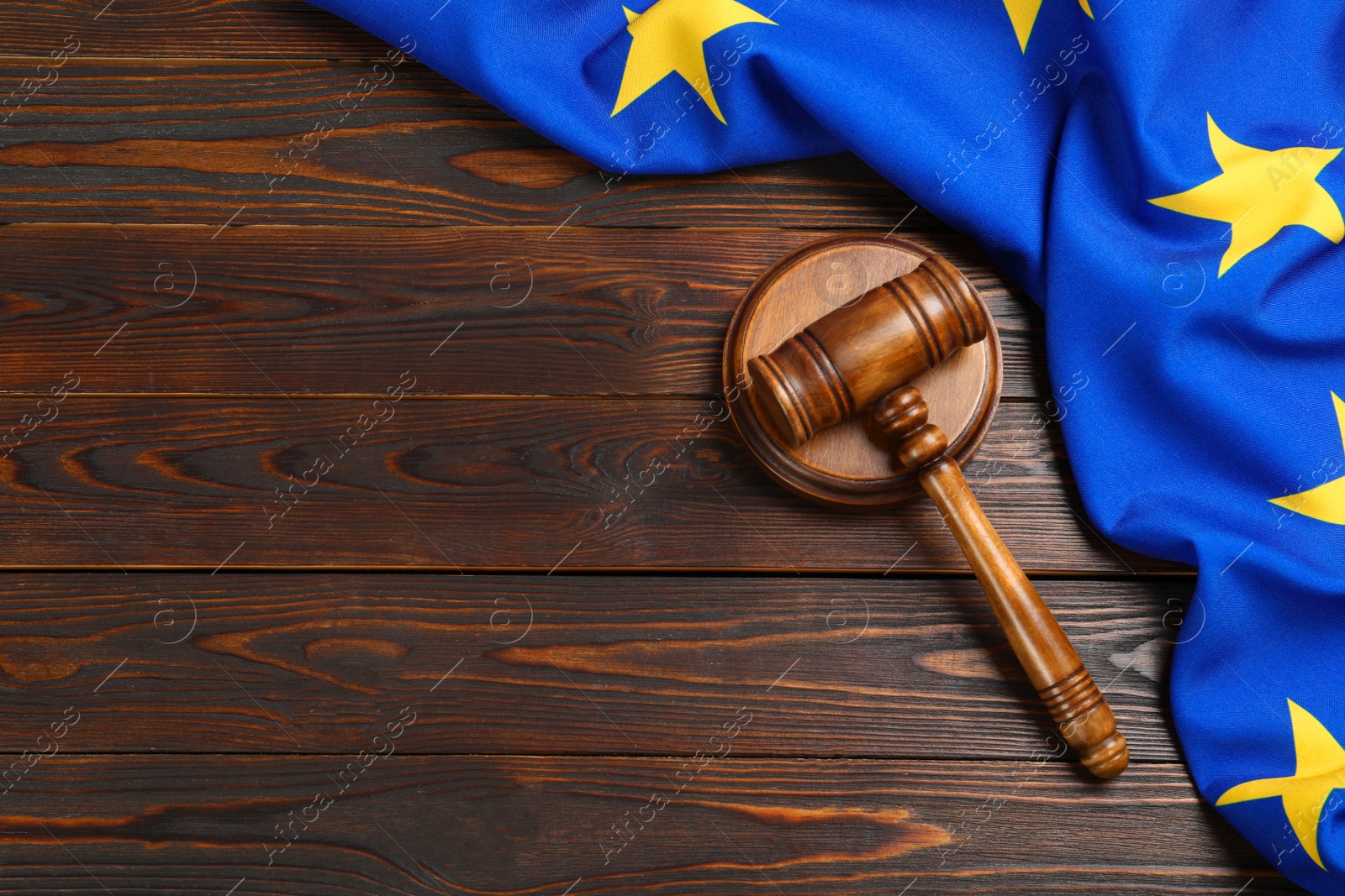 Photo of Judge's gavel and flag of European Union on wooden table, flat lay. Space for text