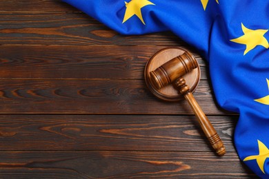 Photo of Judge's gavel and flag of European Union on wooden table, flat lay. Space for text