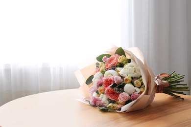 Beautiful flower bouquet on table near window in room. Space for text