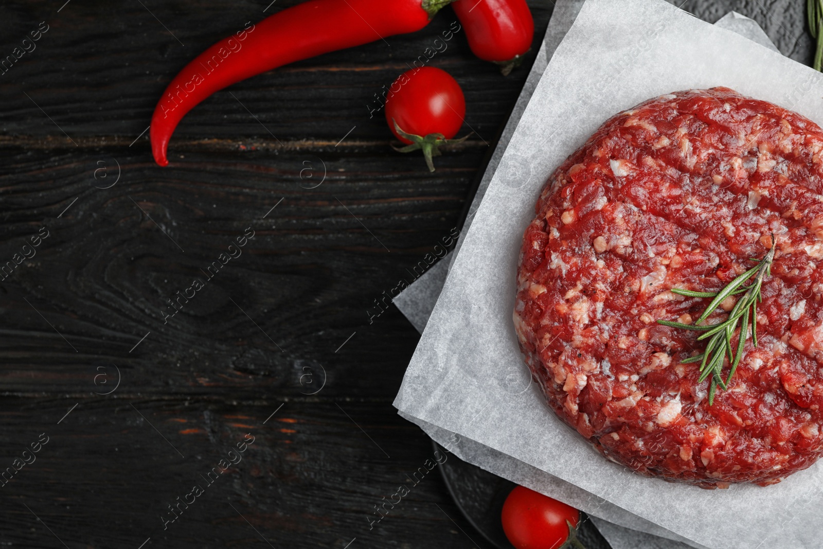 Photo of Flat lay composition with raw meat cutlet for burger on black wooden table. Space for text