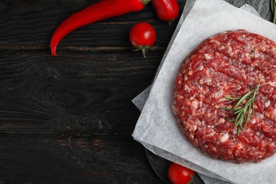Photo of Flat lay composition with raw meat cutlet for burger on black wooden table. Space for text