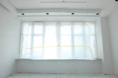 Photo of Big window covered with plastic film in room