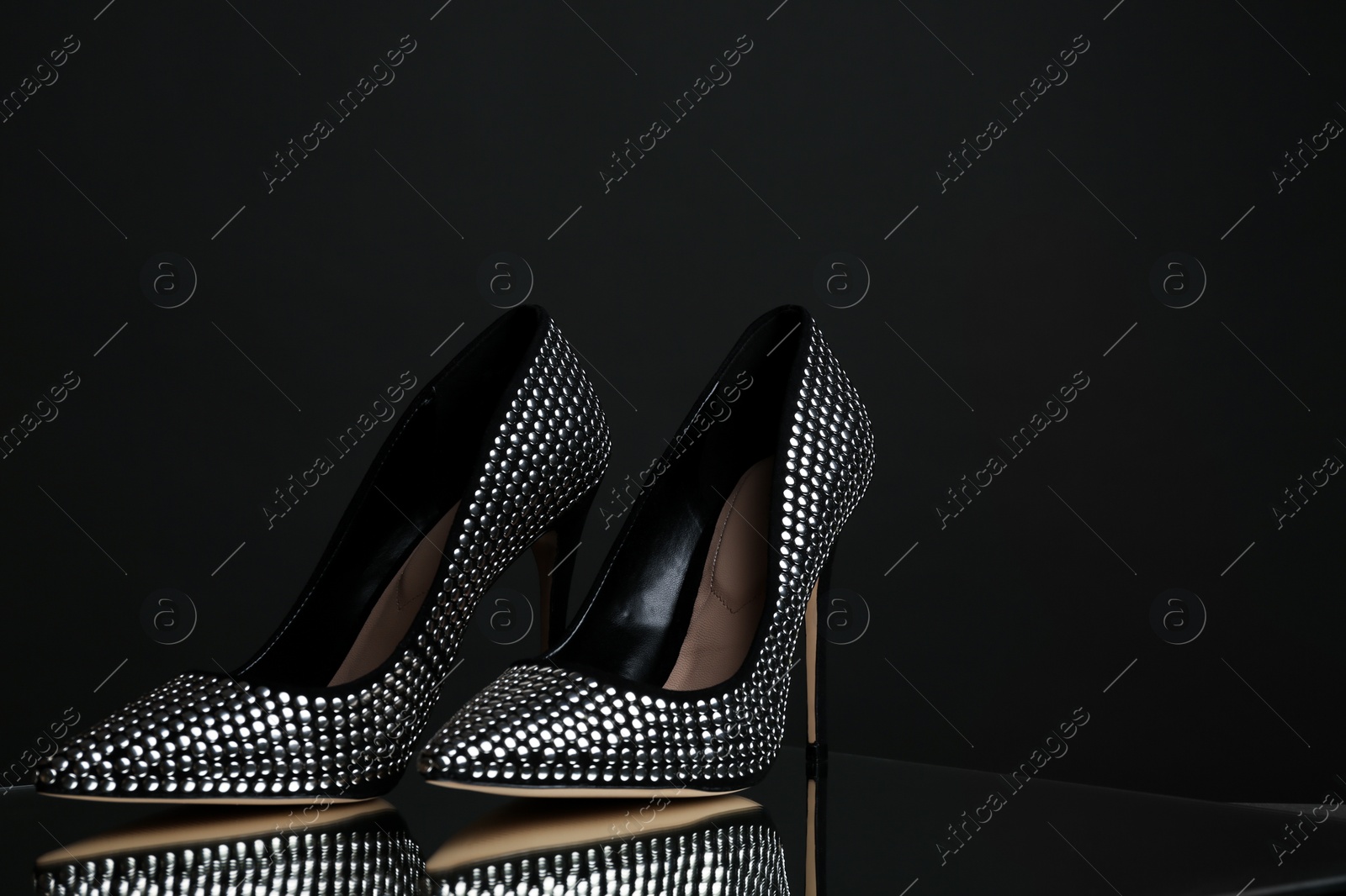 Photo of Stylish high heel shoes on dark background. Space for text