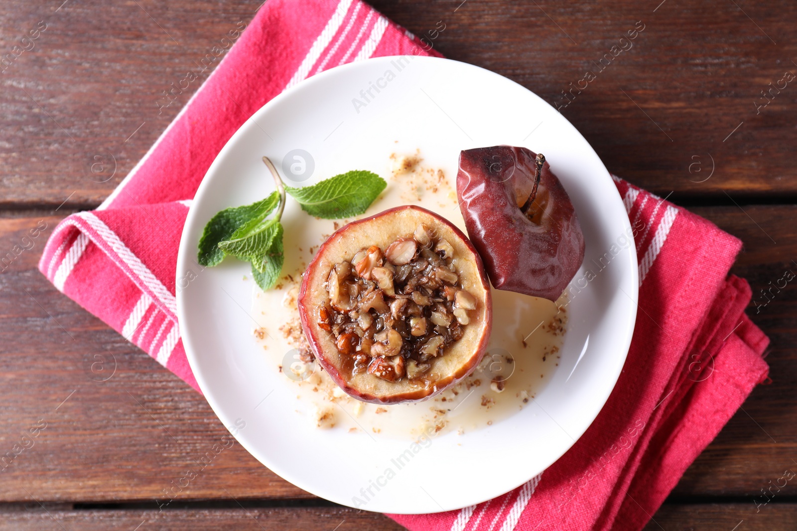 Photo of Tasty baked apple with nuts, honey and mint on wooden table, top view