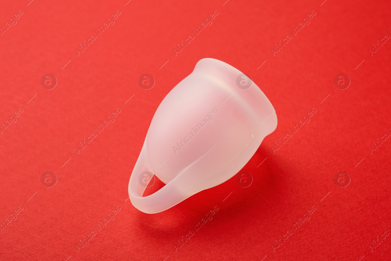 Photo of Menstrual cup on red background. Reusable female hygiene product