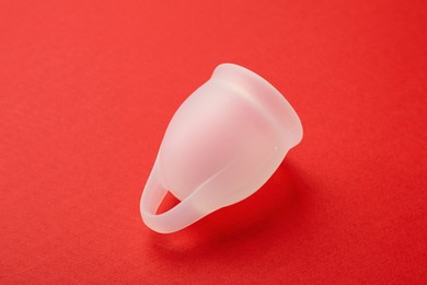 Photo of Menstrual cup on red background. Reusable female hygiene product