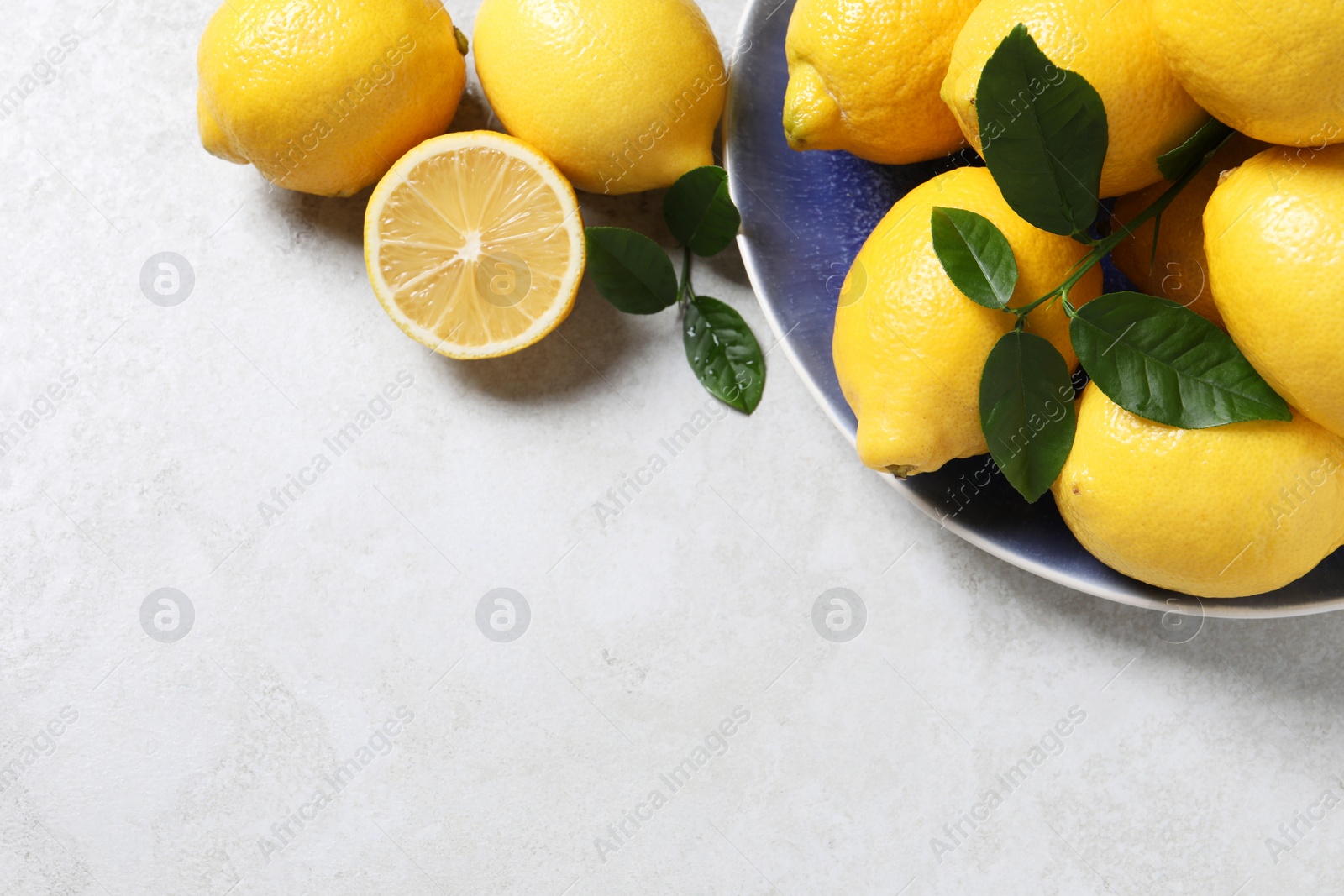 Photo of Fresh lemons and green leaves on table, flat lay. Space for text