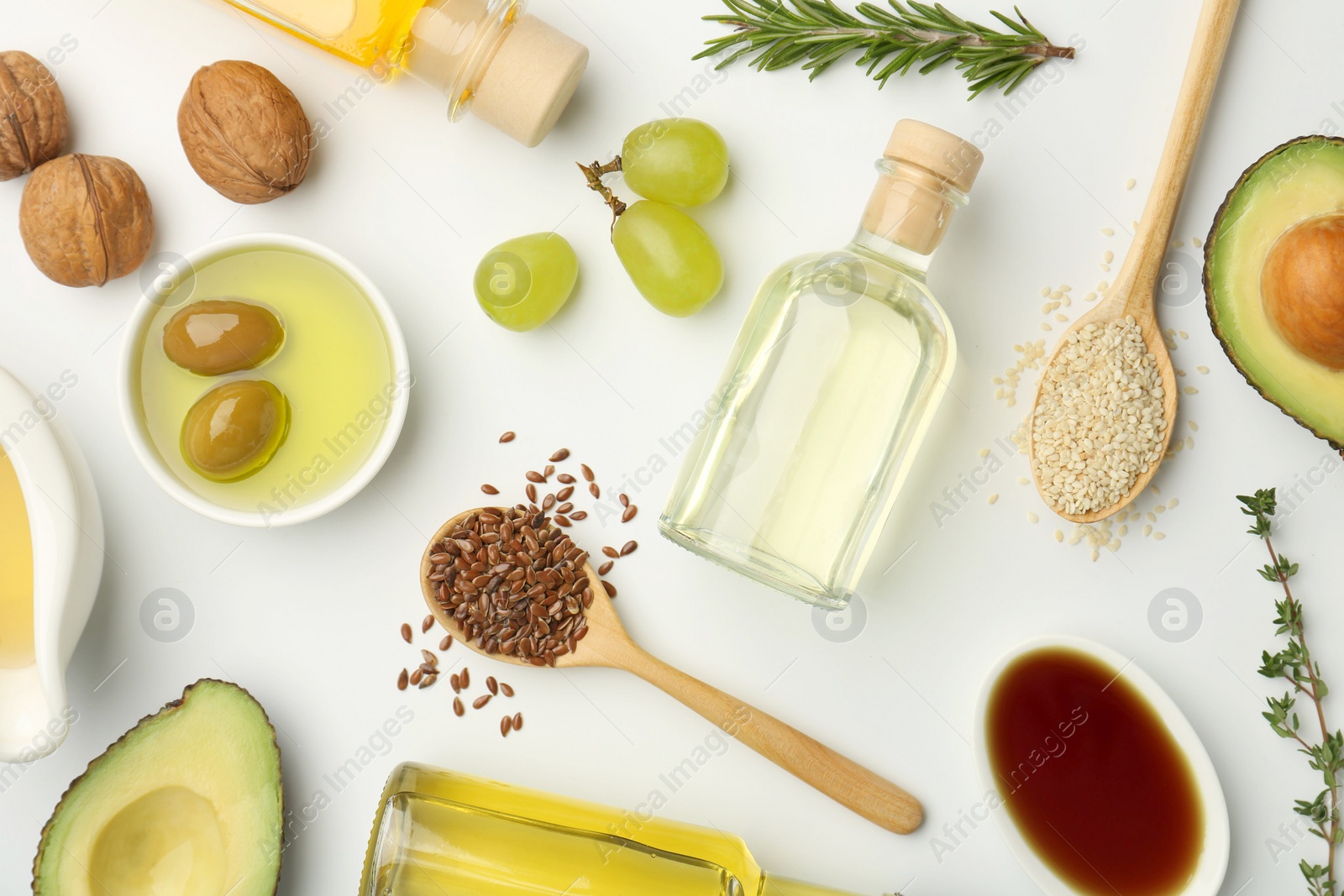 Photo of Vegetable fats. Different oils in glass bottles and ingredients on white table, flat lay