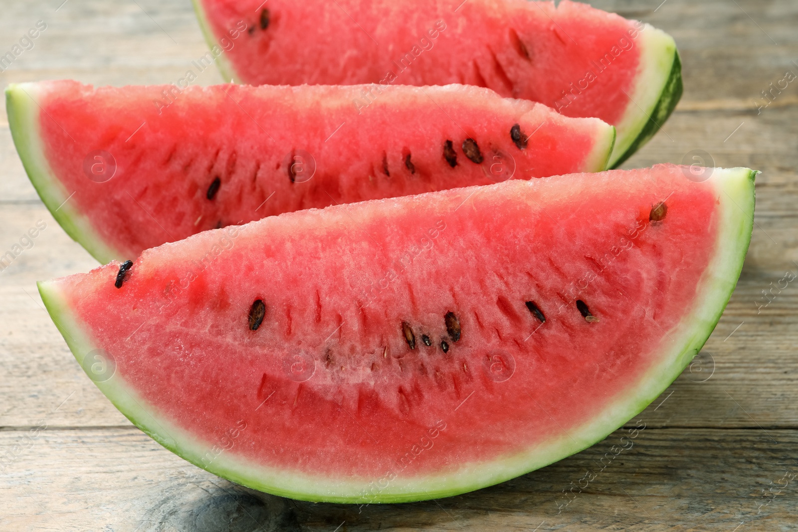 Photo of Slices of tasty ripe watermelon on wooden table, closeup