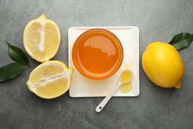 Sweet honey and fresh lemons on grey table, flat lay