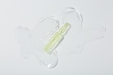 Skincare ampoule on white surface with gel, top view