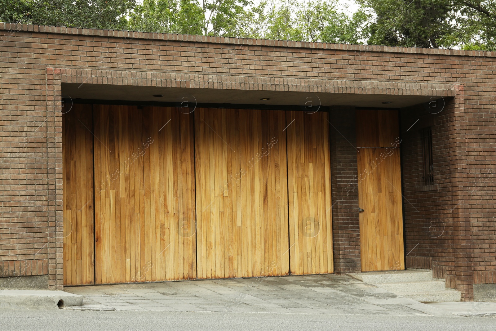 Photo of Brick wall with wooden entrance door and gates. Exterior design