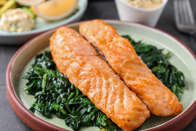 Photo of Tasty salmon with spinach on table, closeup