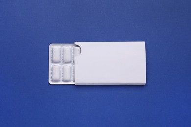 Photo of Blister with chewing gums on blue background, top view
