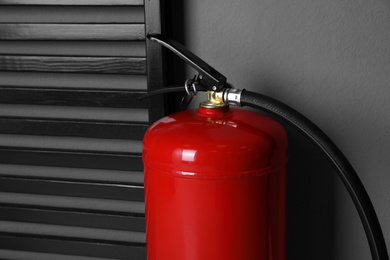 Photo of Fire extinguisher near grey wall indoors, closeup