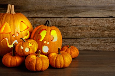 Image of Spooky jack o`lanterns on wooden table, space for text. Halloween decor