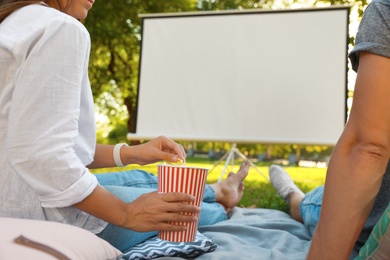 Photo of Couple with popcorn watching movie in open air cinema, closeup. Space for text