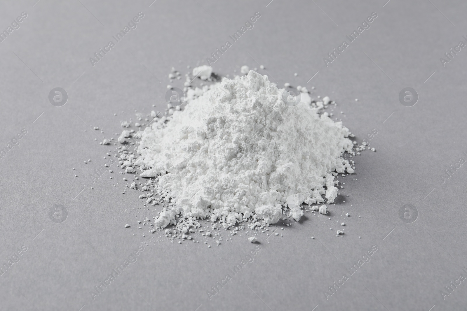 Photo of Heap of calcium carbonate powder on light grey table, closeup