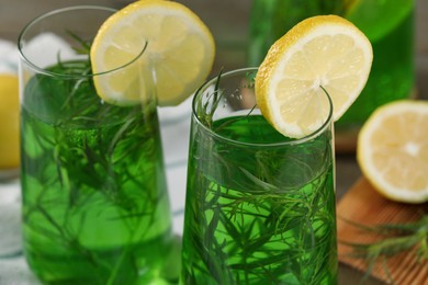 Photo of Glasses of refreshing tarragon drink with lemon slices on table, closeup
