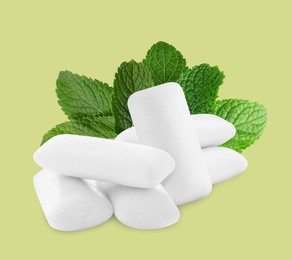 Image of Menthol chewing gum pillows and mint leaves on pale light yellowish green background
