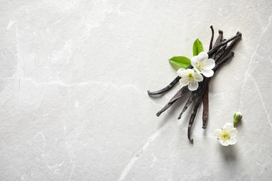 Photo of Vanilla sticks and flowers on light background