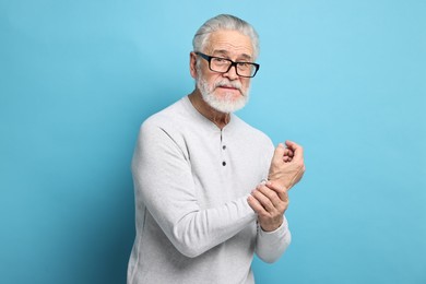 Photo of Arthritis symptoms. Man suffering from pain in wrist on light blue background