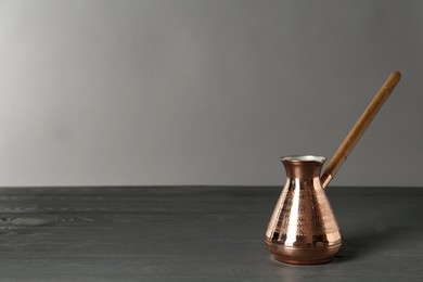 Photo of Copper turkish coffee pot on grey wooden table, space for text